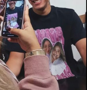 Cliente mostrando a foto da camisa personalizada no celular